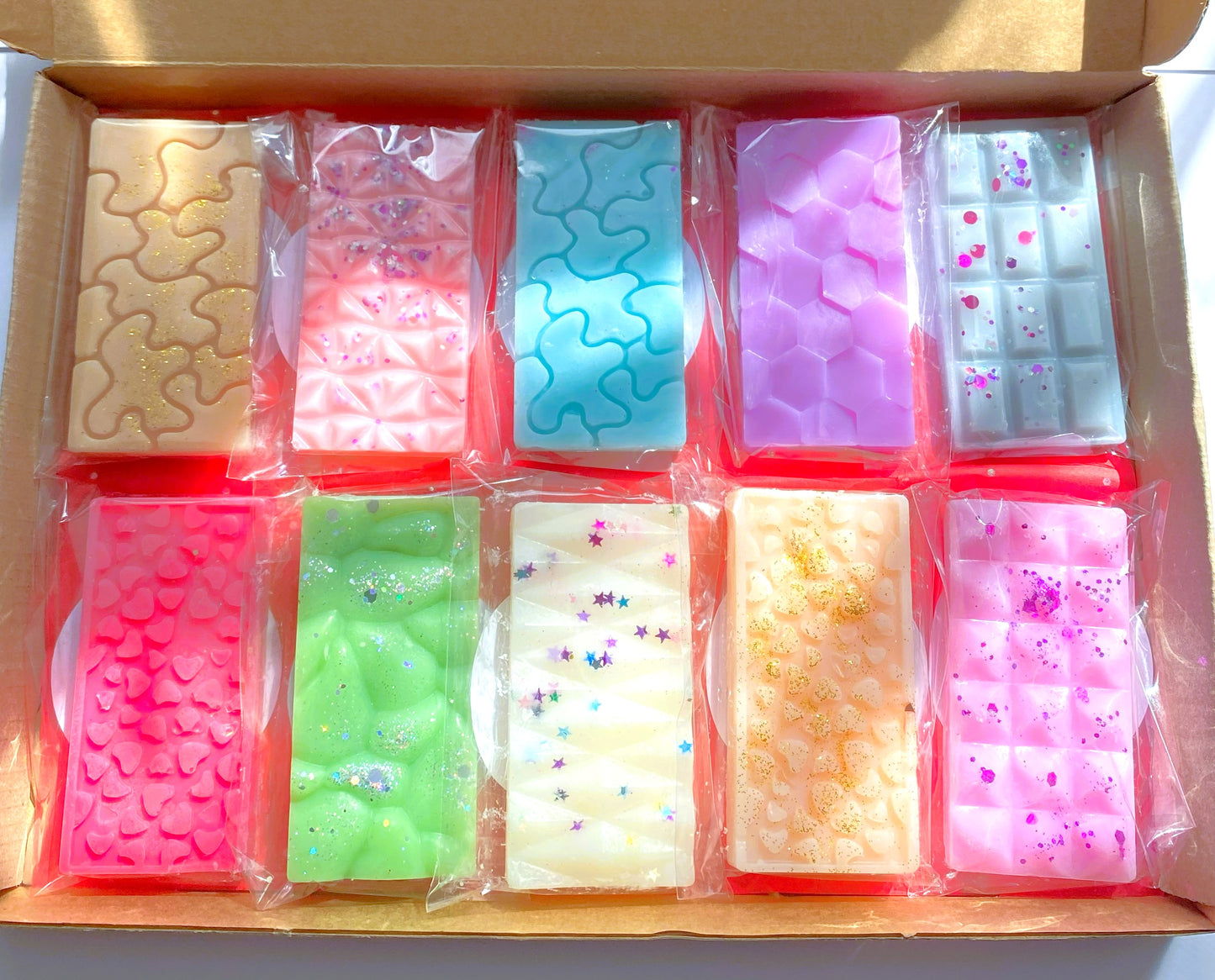 A box containing multiple small, rectangular wax melt bars in various colors, each with a different fragrance.