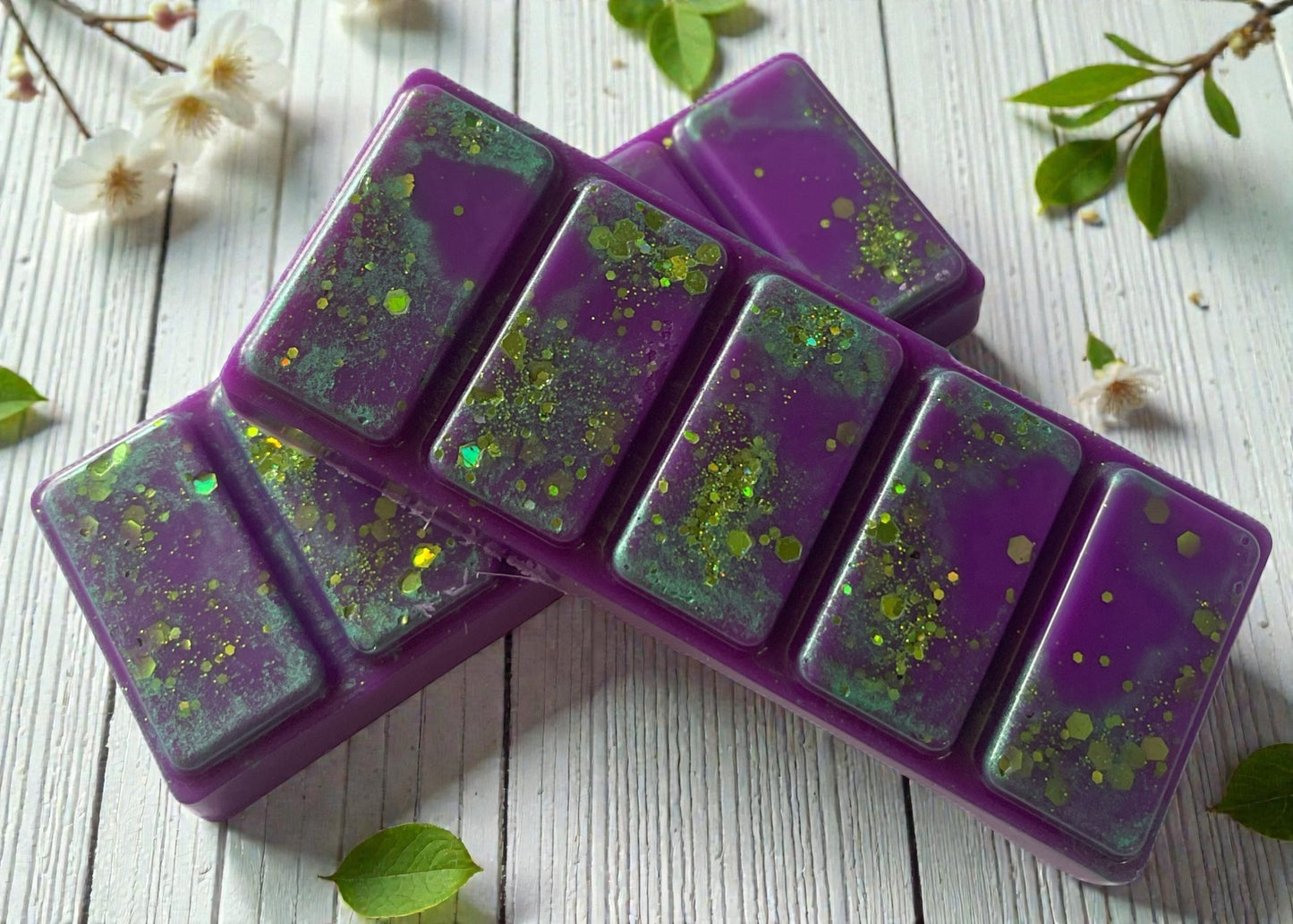 Purple silicone mold with green speckles on a wooden surface with flowers and leaves.