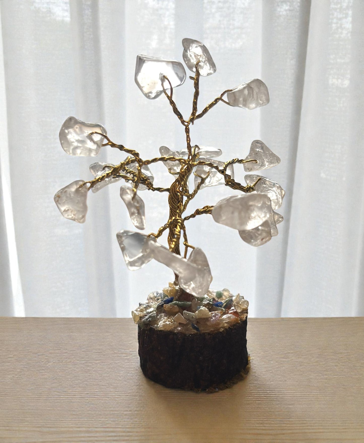 Crystal tree-like sculpture on a wooden surface with a white curtain background