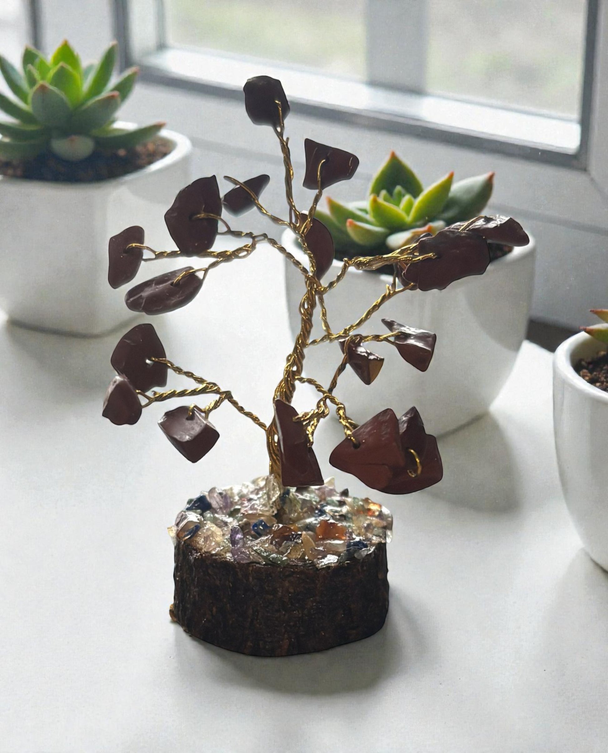 Decorative tree with brown leaves on a white surface with potted plants in the background.