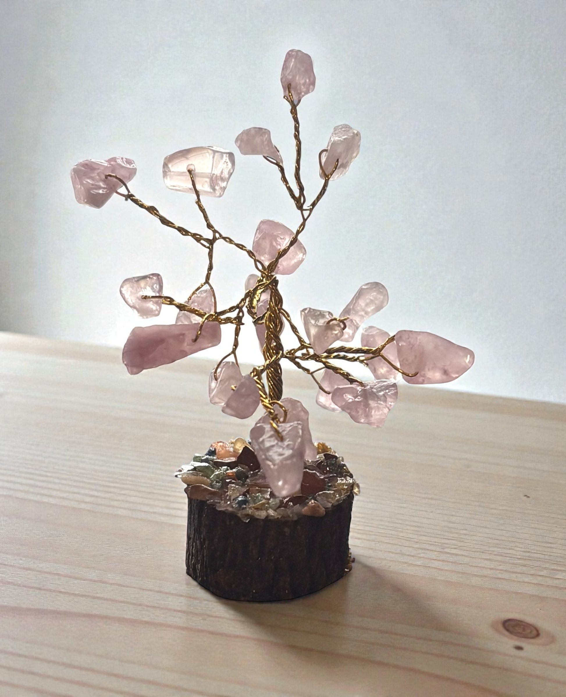 Small decorative tree made of pink crystals on a wooden base with a light background
