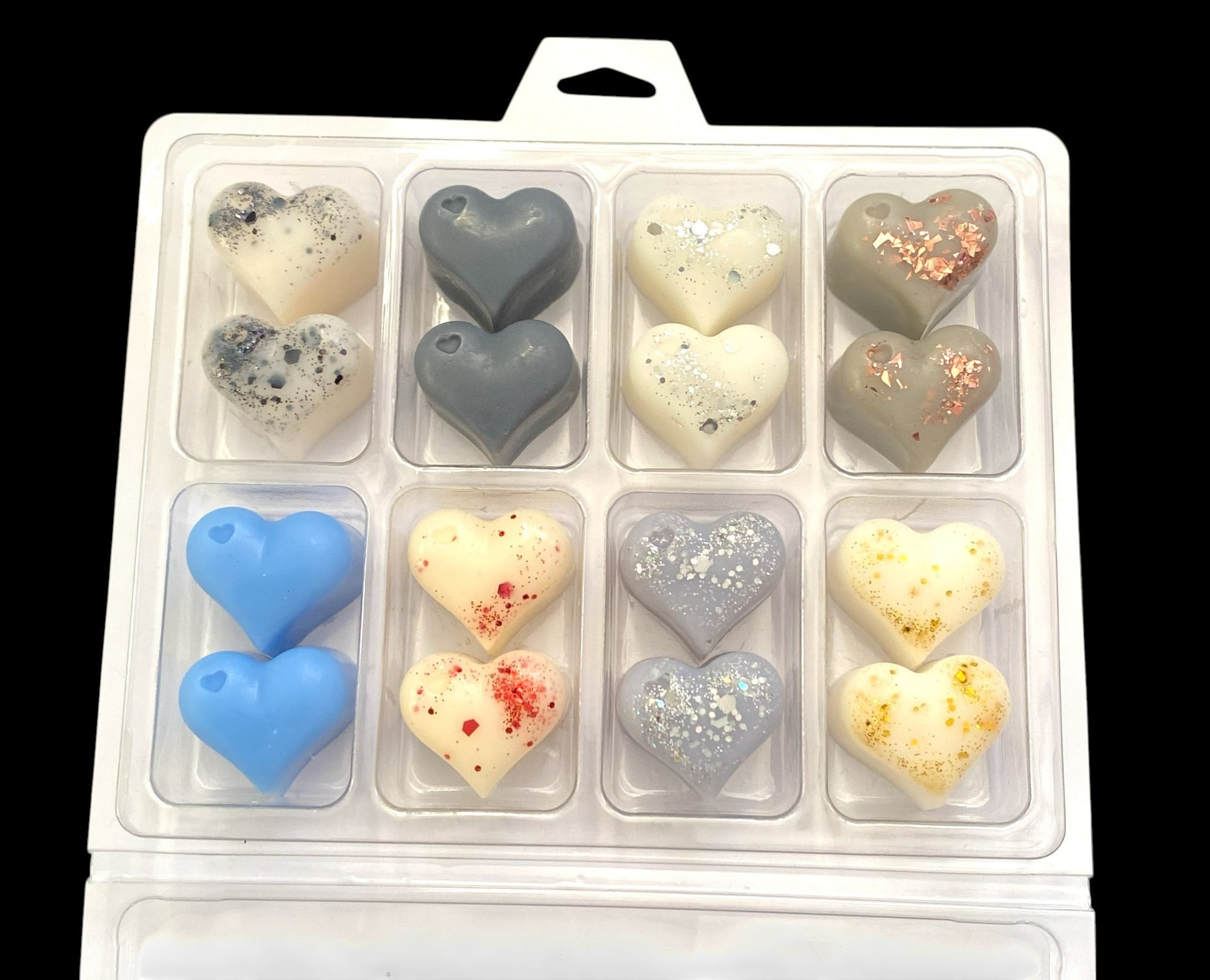 A box of heart-shaped wax melts in various colors and patterns, inspired by designer aftershave fragrances.