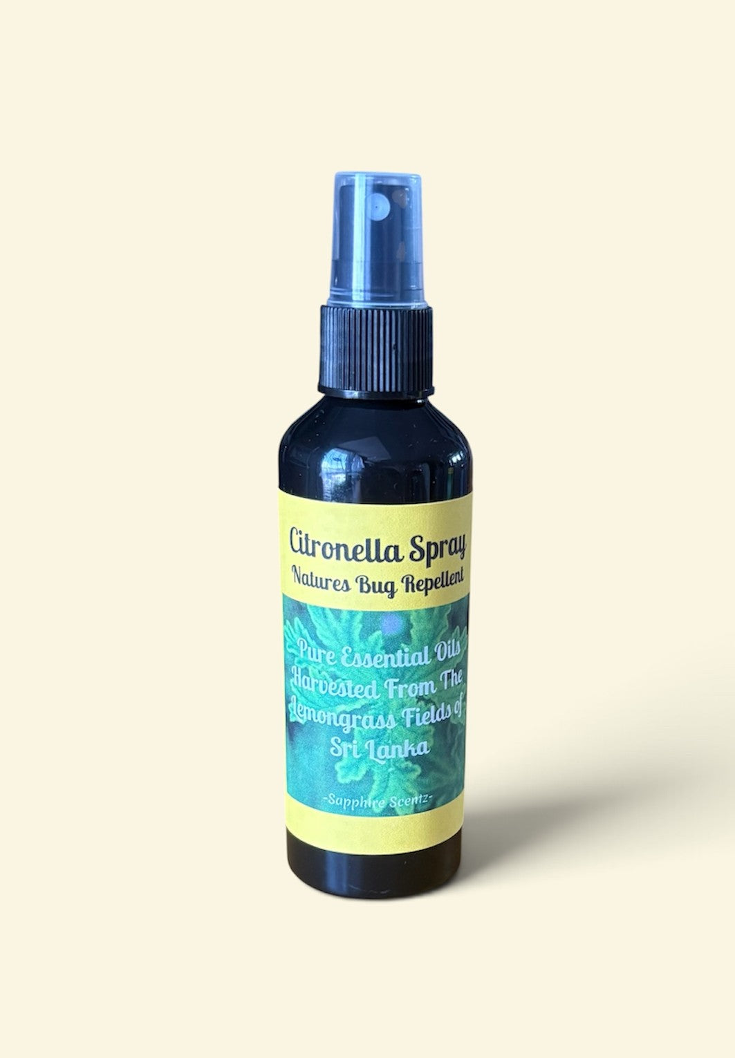 A bottle of Nature's Bug Repellent Citronella Spray with a blue spray top and a yellow and green label, set against a solid cream background.