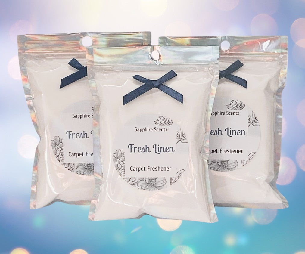 Three packets of 'Fresh Linen' carpet freshener with a blue ribbon on each, set against a bokeh background.