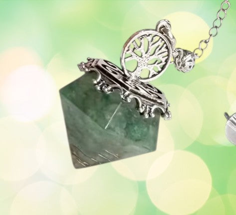 Necklace with a green stone pendant and silver tree of life charm on a blurred green background