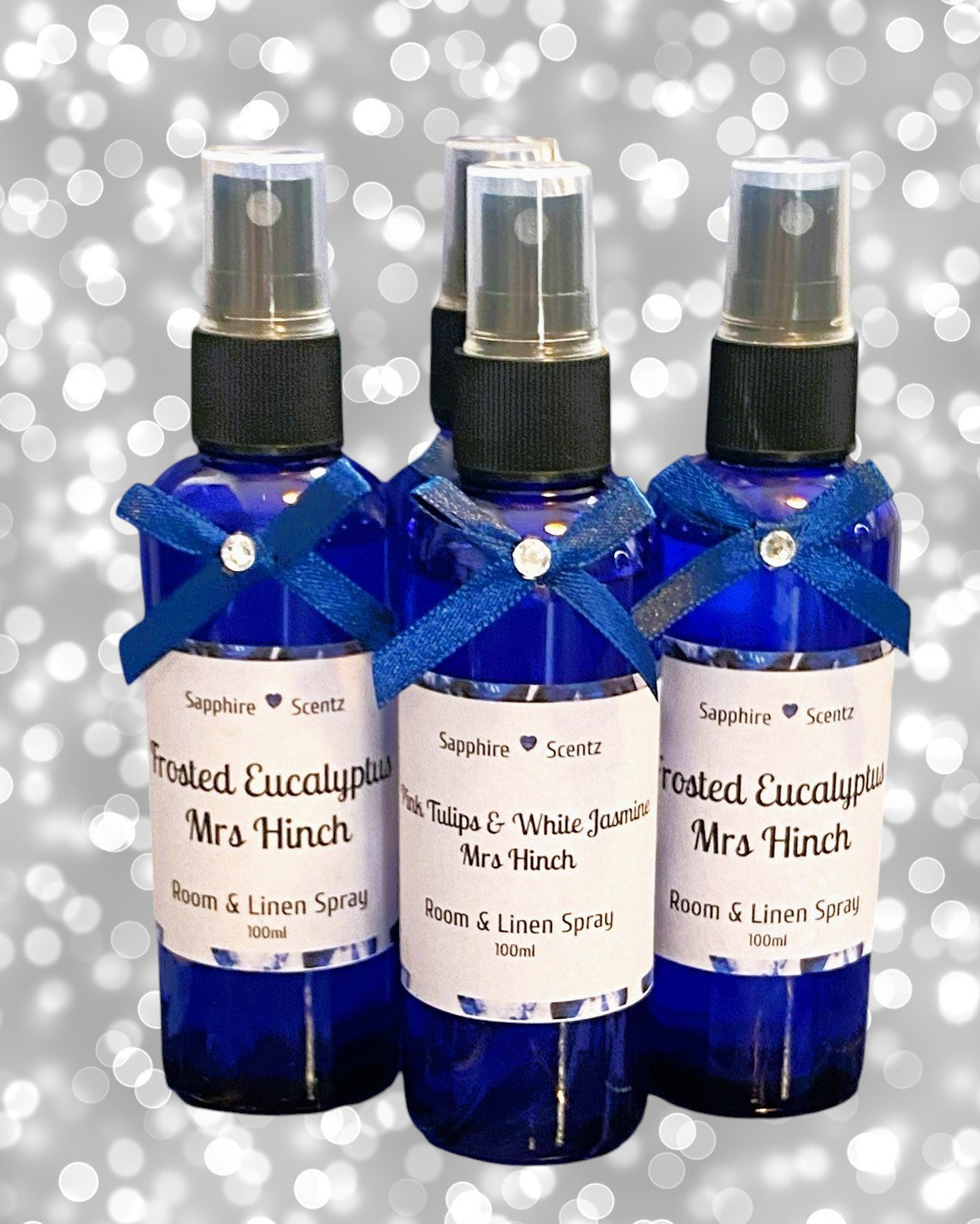 Three blue pump bottles of 'Mrs Hinch Inspired' room and linen spray, each labeled with different scents such as 'Pink Tulip & White Jasmine' and 'Fresh Linen'.