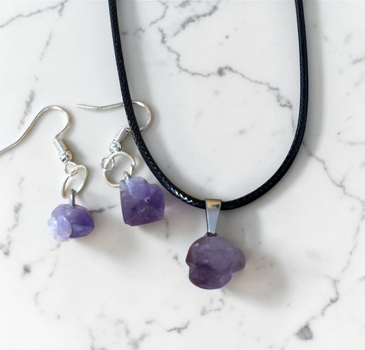Necklace and earrings with purple beads on a marble surface