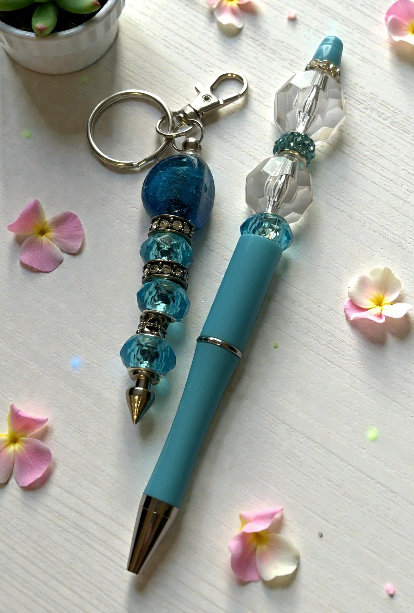 Blue pen with decorative keychain on a light surface with flowers