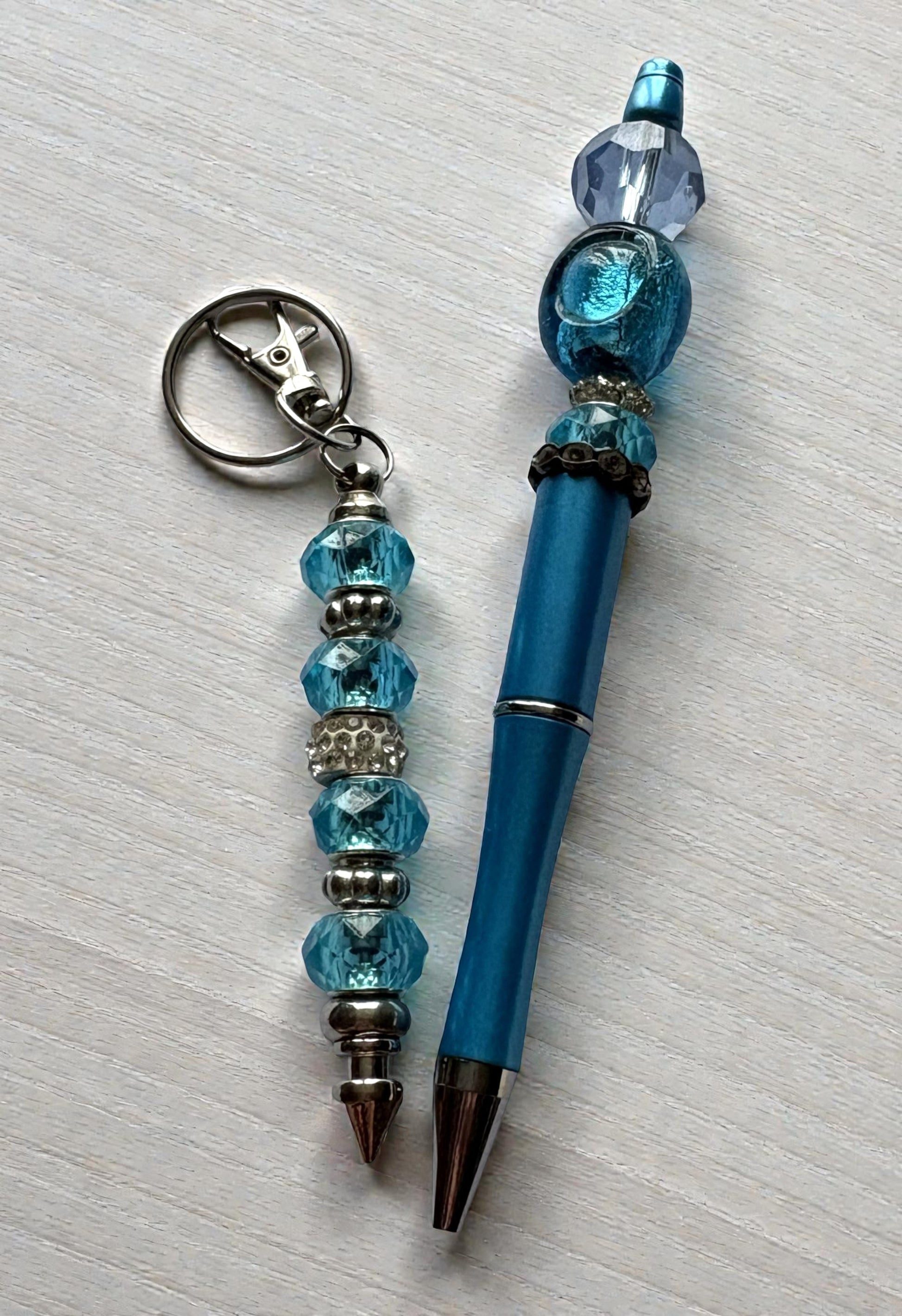 Blue pen with decorative beads and a matching keychain on a light gray background