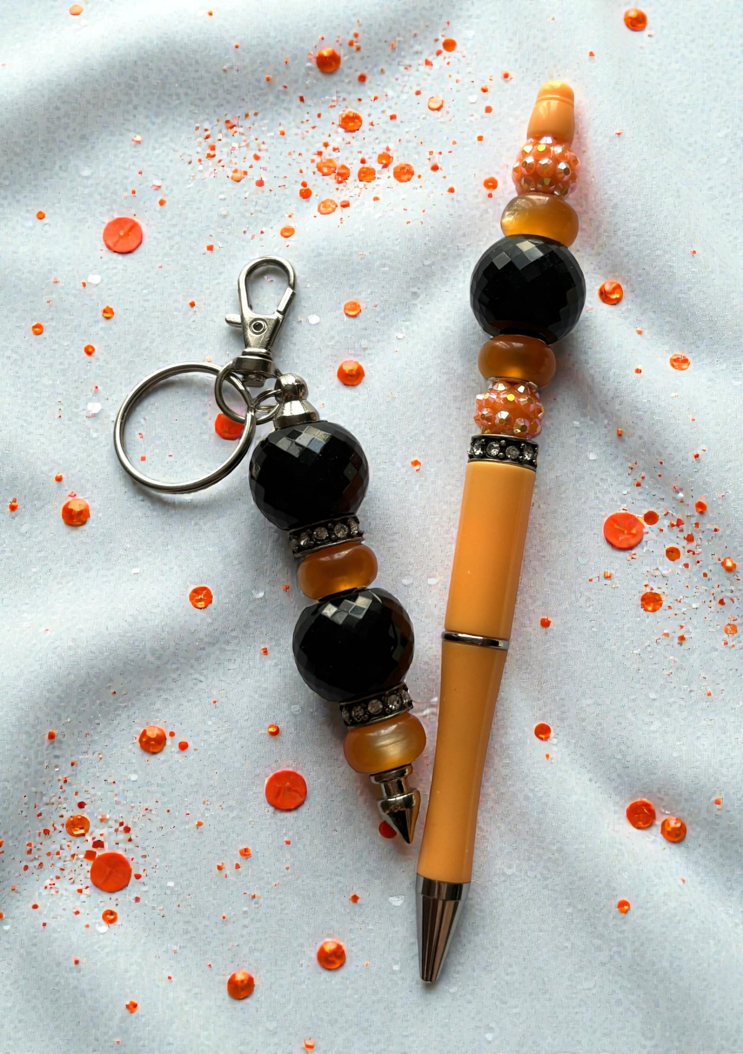 Beaded keychain and pen on a light gray background with orange accents
