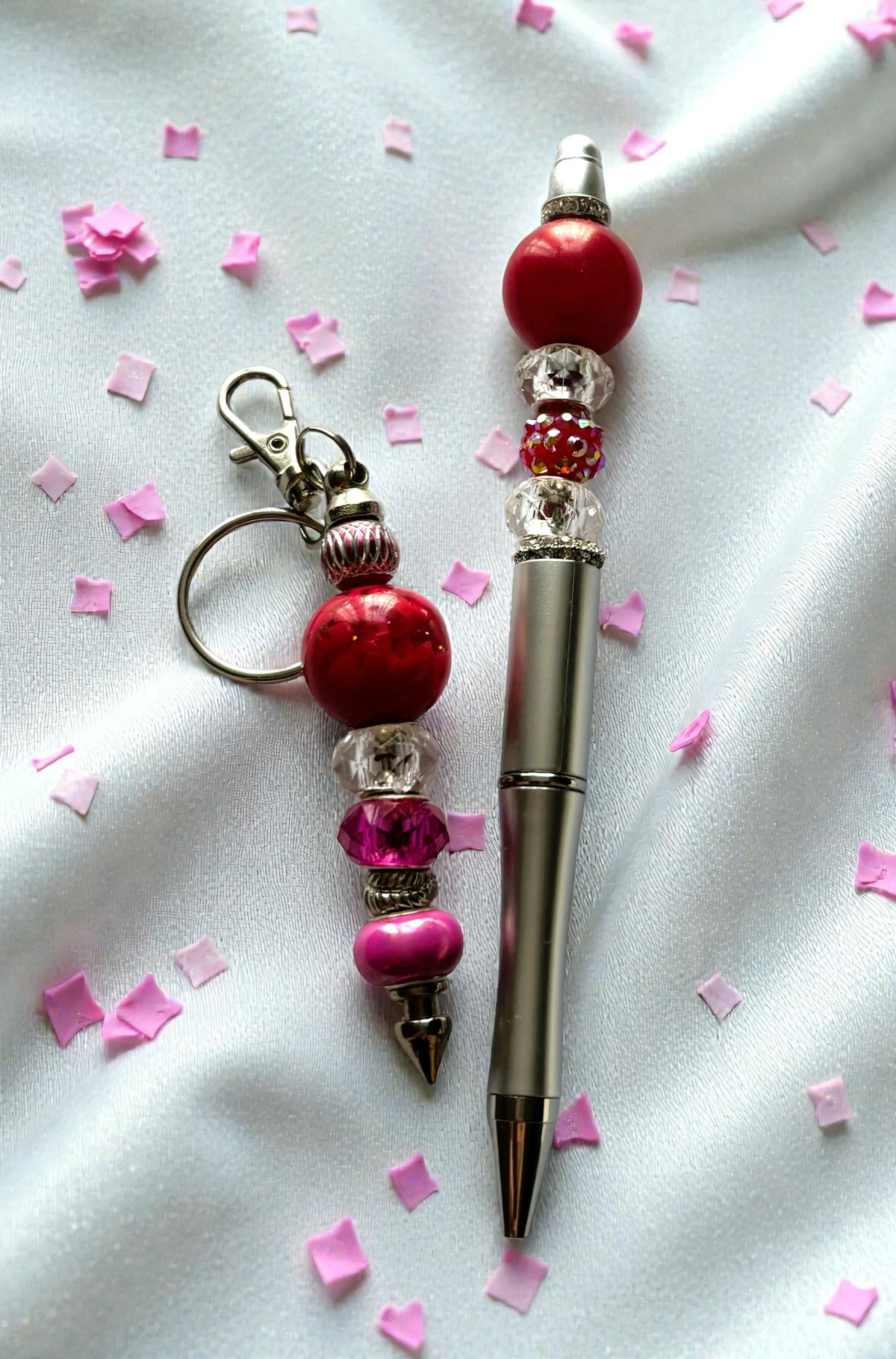 Pen with decorative beads and keychain on a white background with pink confetti