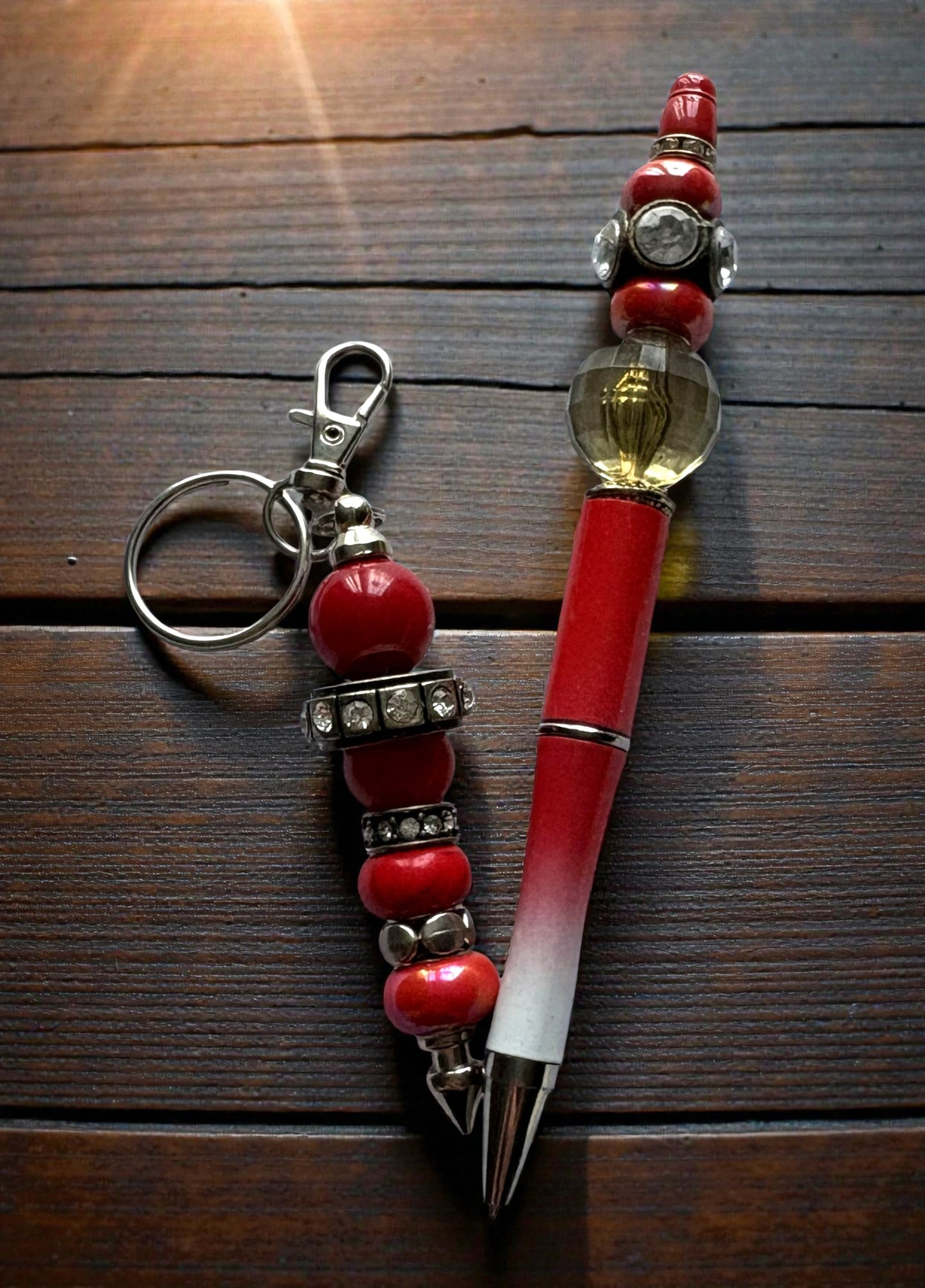 Pen with decorative red bead holder and keychain on wooden surface