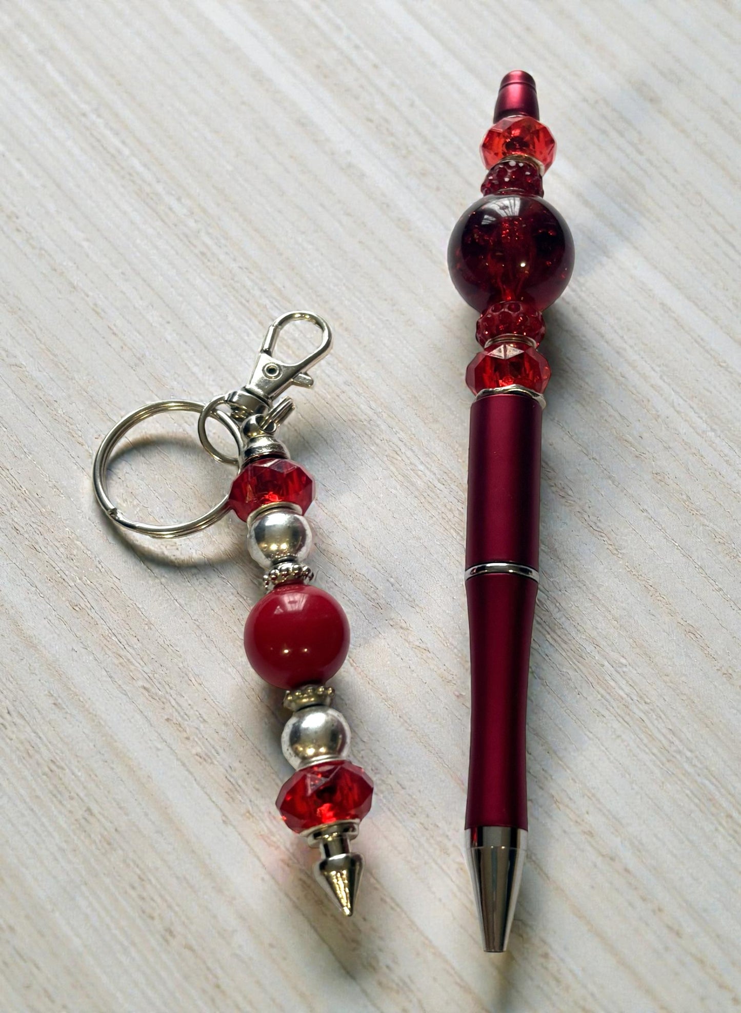 Red beaded keychain and pen on a light wooden surface