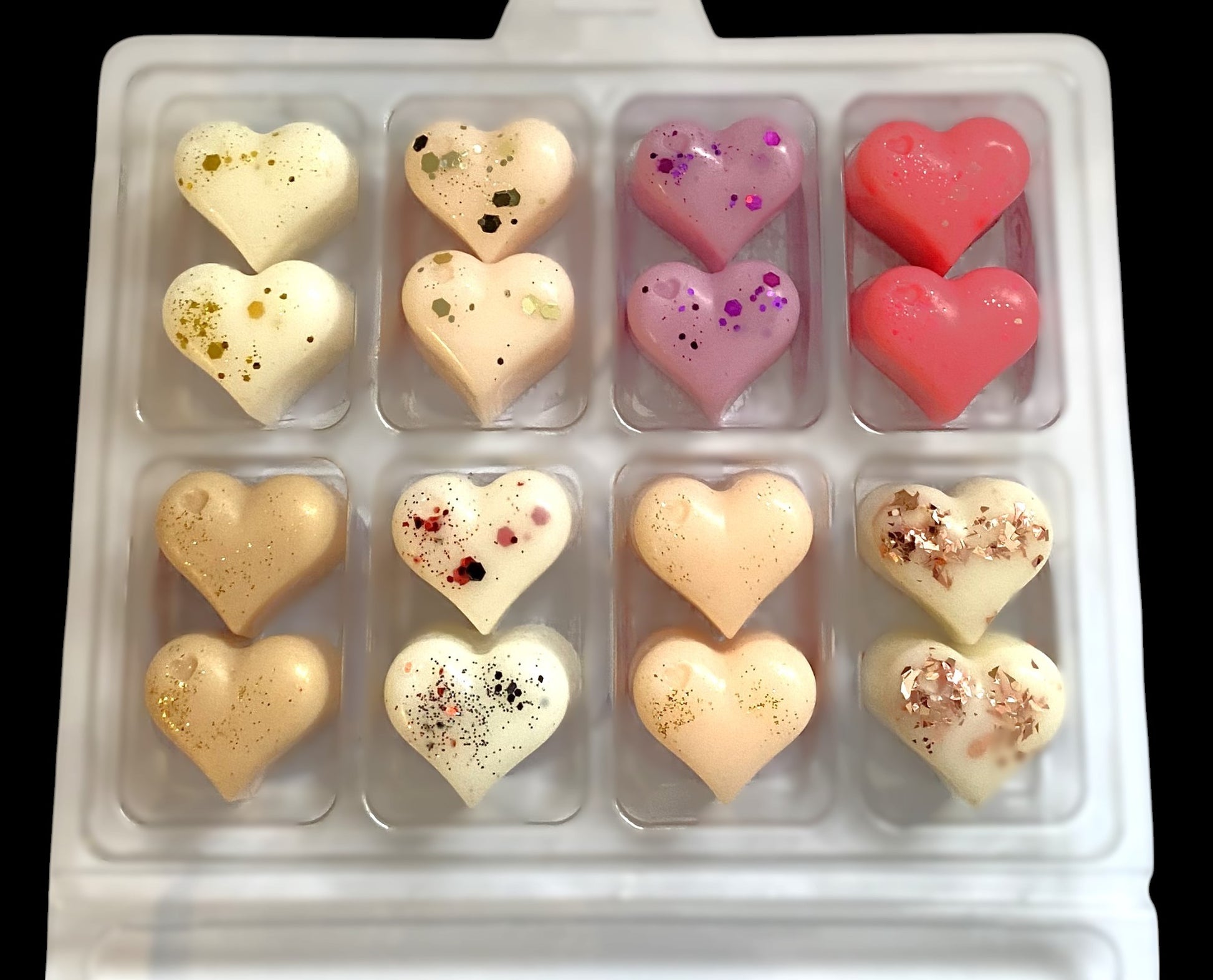 A box containing 16 heart-shaped wax melts in various colors and patterns, inspired by designer perfumes.
