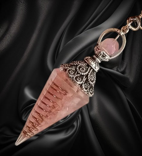 Decorative keychain with pink crystal and gold accents on black fabric background