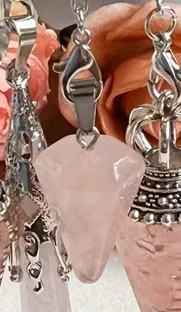 Close-up of silver earrings with a pink stone against a blurred floral background