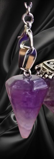 Purple crystal pendant with silver chain on a dark background
