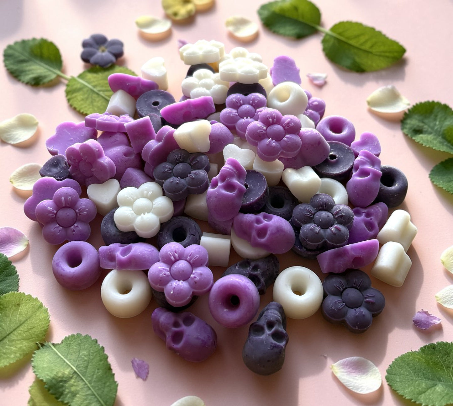 Colorful fruit-shaped candies on a pink background with leaves and petals.