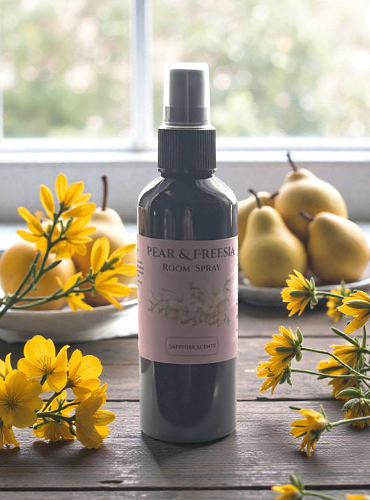 Room spray bottle labeled 'Pear & Freesia' with yellow flowers and pears in the background.