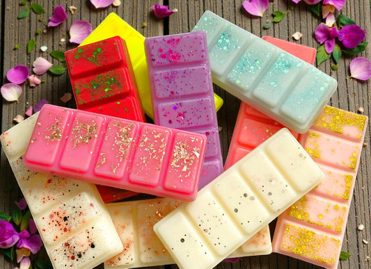 Colorful soap bars with various textures and designs on a wooden surface with flowers.