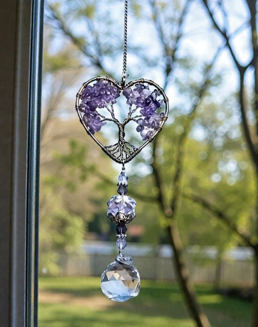 Heart-shaped crystal decoration with tree of life design hanging by a window